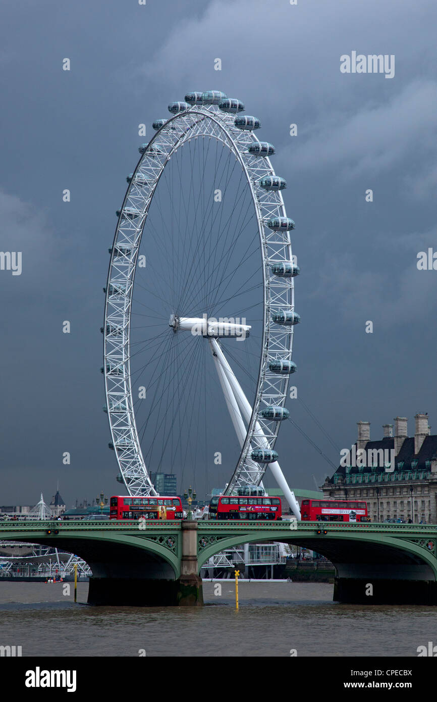 London eye, Millennium wheel with red buses and Westminster bridge against dark storm sky, London, England. Stock Photo
