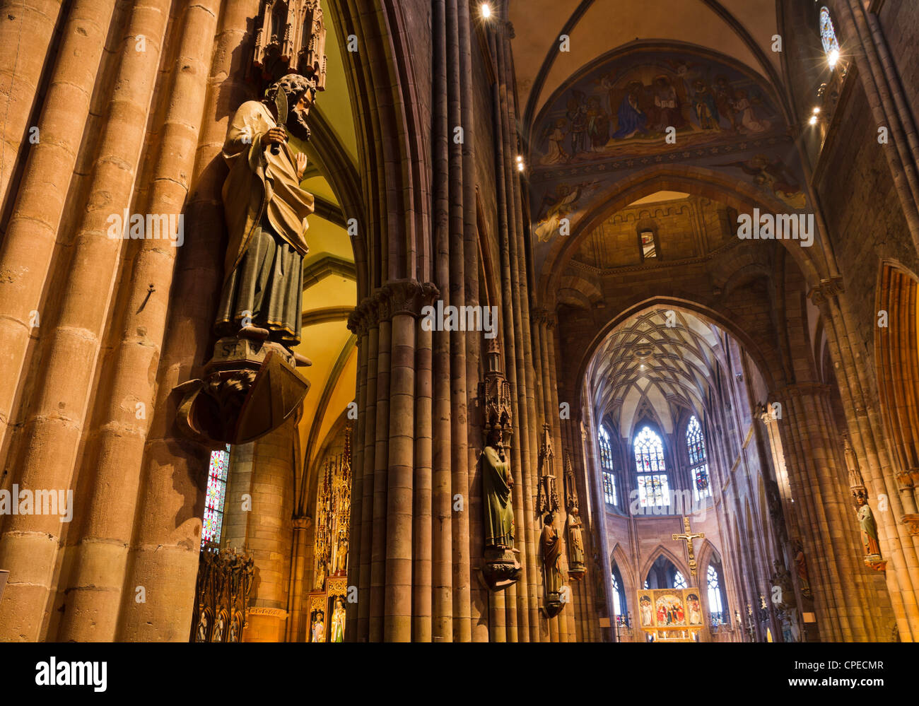 Interior with high ceilings, pillars, stained glass windows, carved decoration figures of gothic Muenster, Freiburg Stock Photo