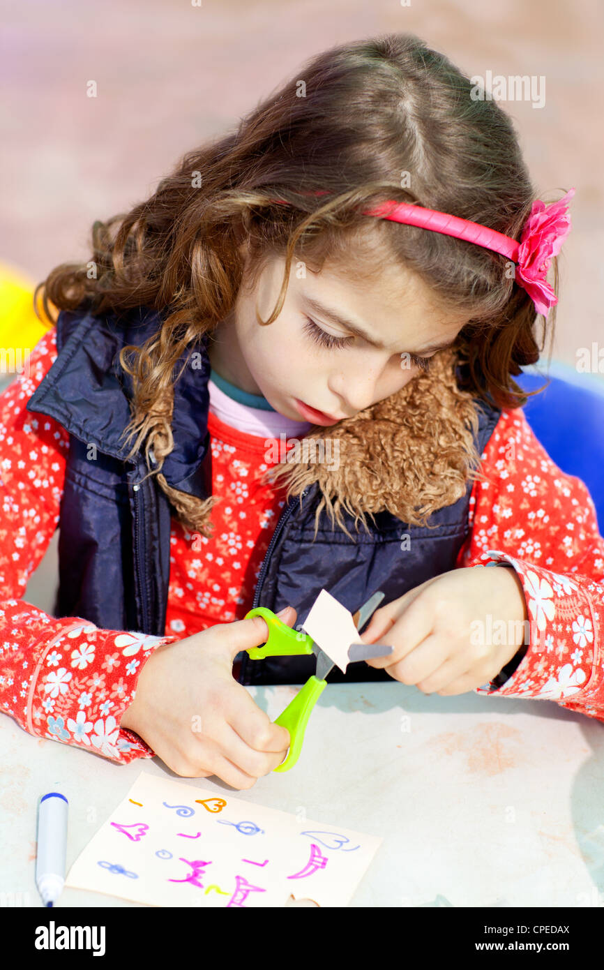 little kid girl working at school doing art work workshop cutting with ...