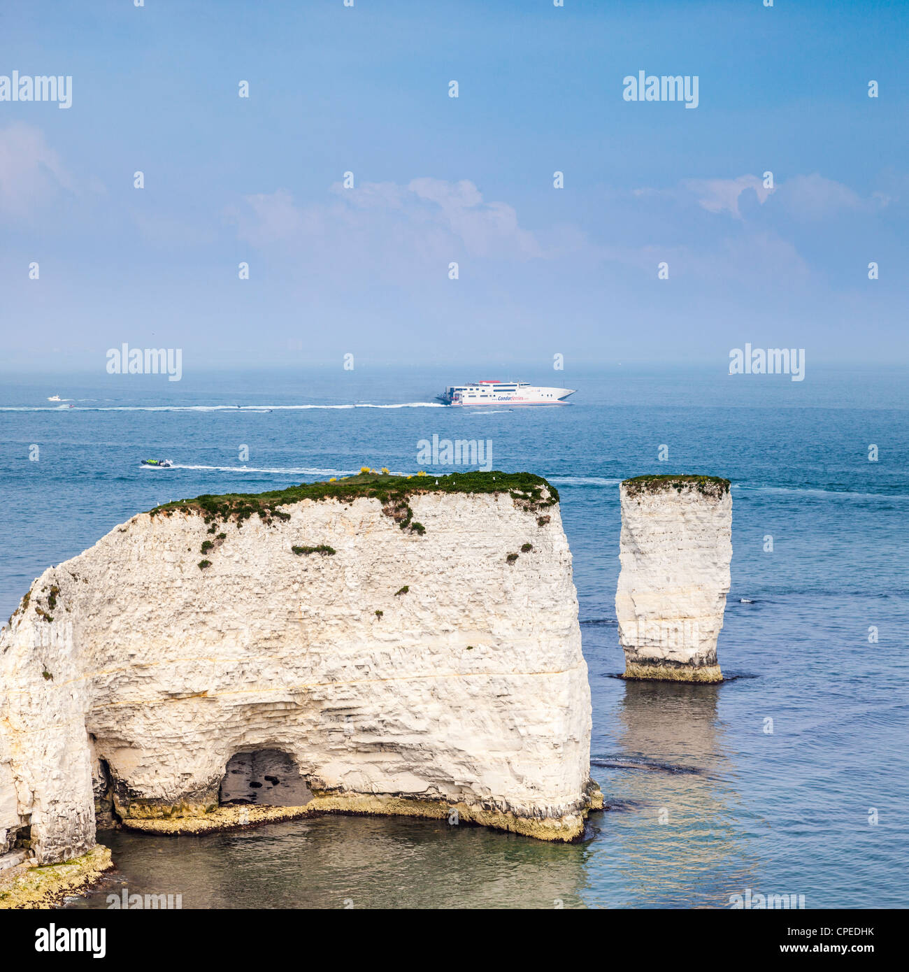 The Old Harry Rocks near Swanage in Dorset, England, with a catamaran fast ferry and other boats passing in the background. Stock Photo