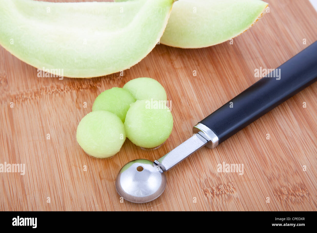 https://c8.alamy.com/comp/CPEDXR/fresh-honeydew-melon-balls-on-cutting-board-with-melon-baller-CPEDXR.jpg