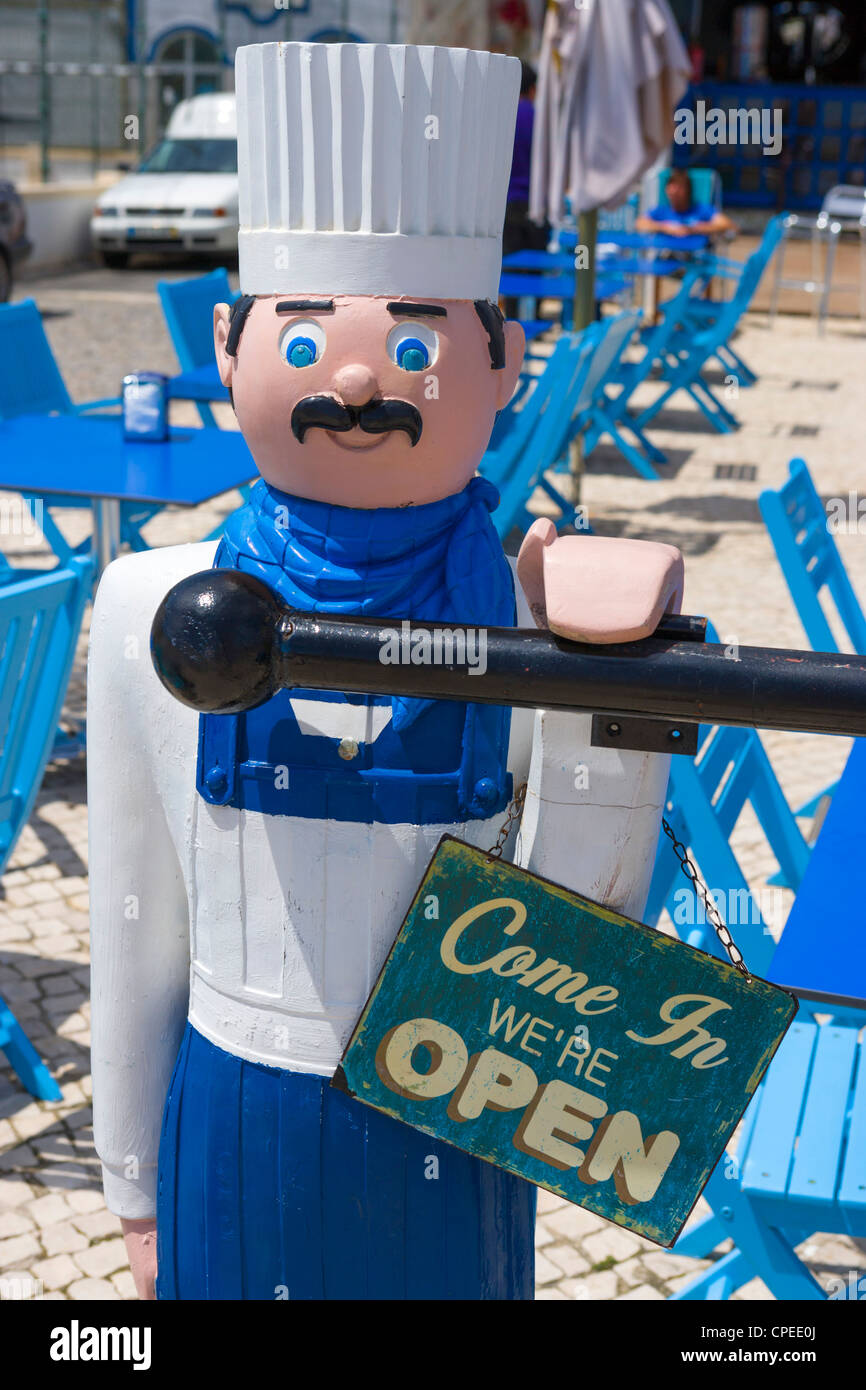 Mannequin of a chef displaying a 'Come In We're Open' sign outside a restaurant, Cabanas, near Tavira, Algarve, Portugal Stock Photo