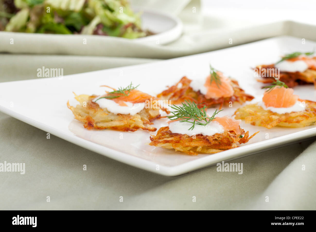 Bite sized potato rosti appetizer topped with fresh sour cream, smoked ...