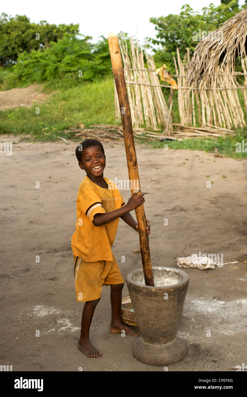 Young boy crushing maize in Guludo village in the Quirimbas National Park in northern Mozambique. Stock Photo