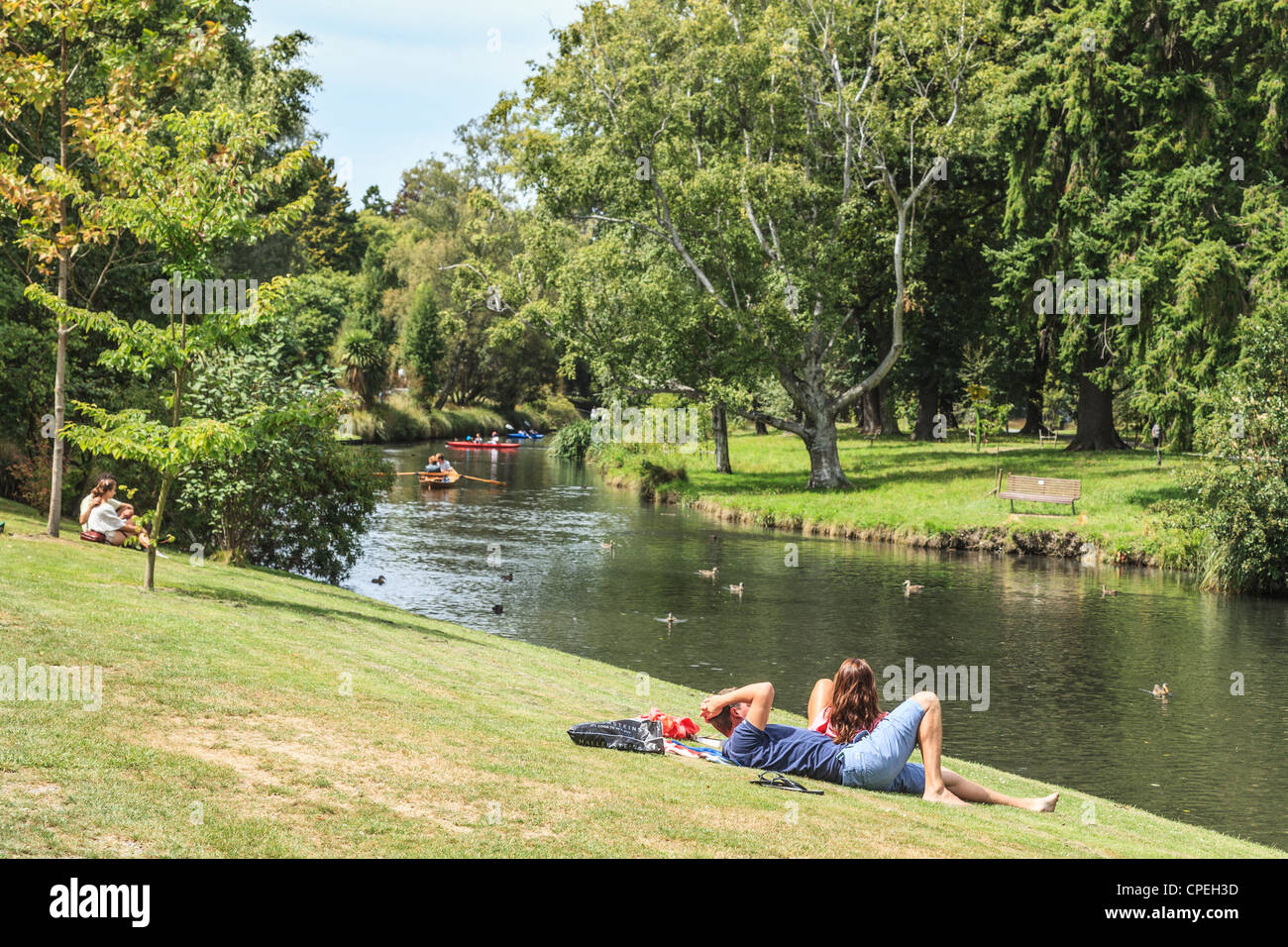People relaxing on the banks of the Avon River in Hagley Park., Christchurch, New Zealand, Stock Photo