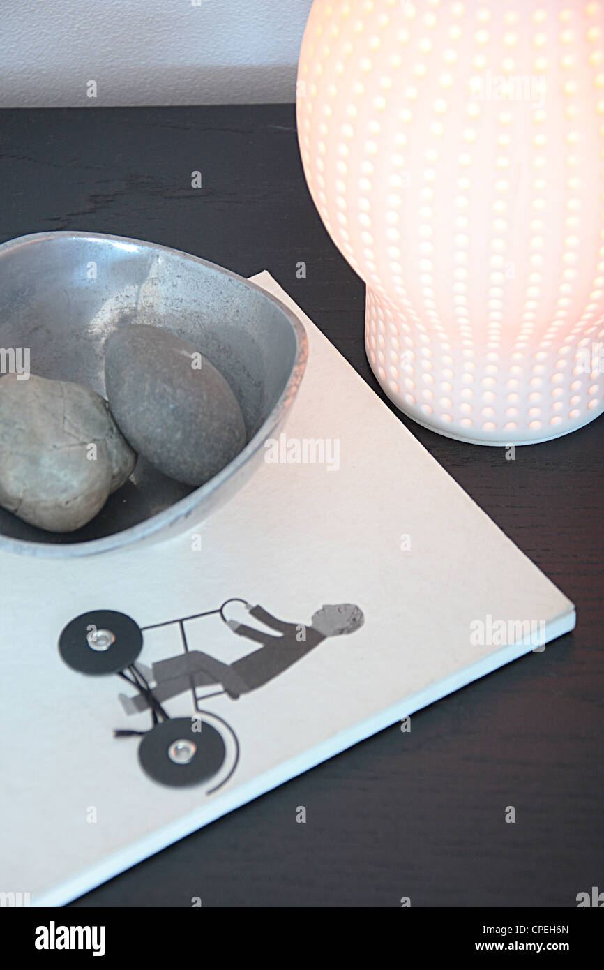 Book, Pebbles In Bowl And Lamp On Table Stock Photo
