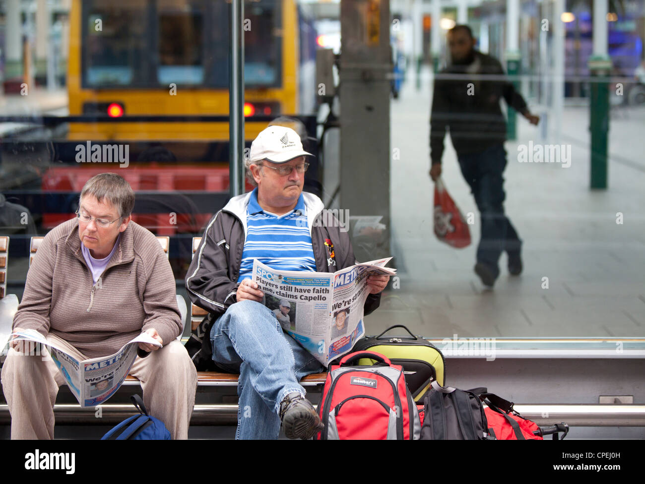 Manchester Piccadilly railway station passengers reading in waiting area Stock Photo