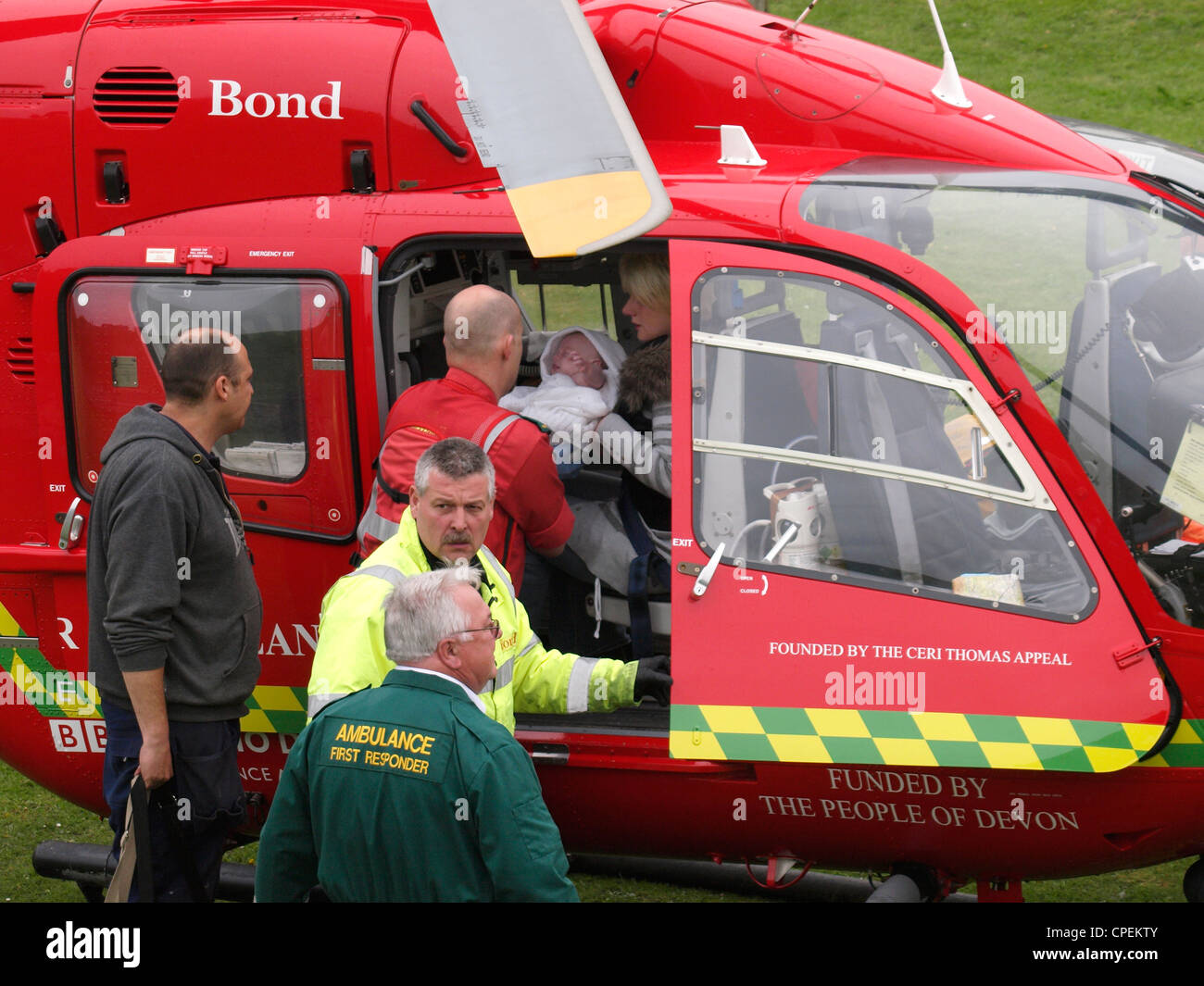 Medic handing baby to mother in helicopter of Devon air ambulance, UK Stock Photo