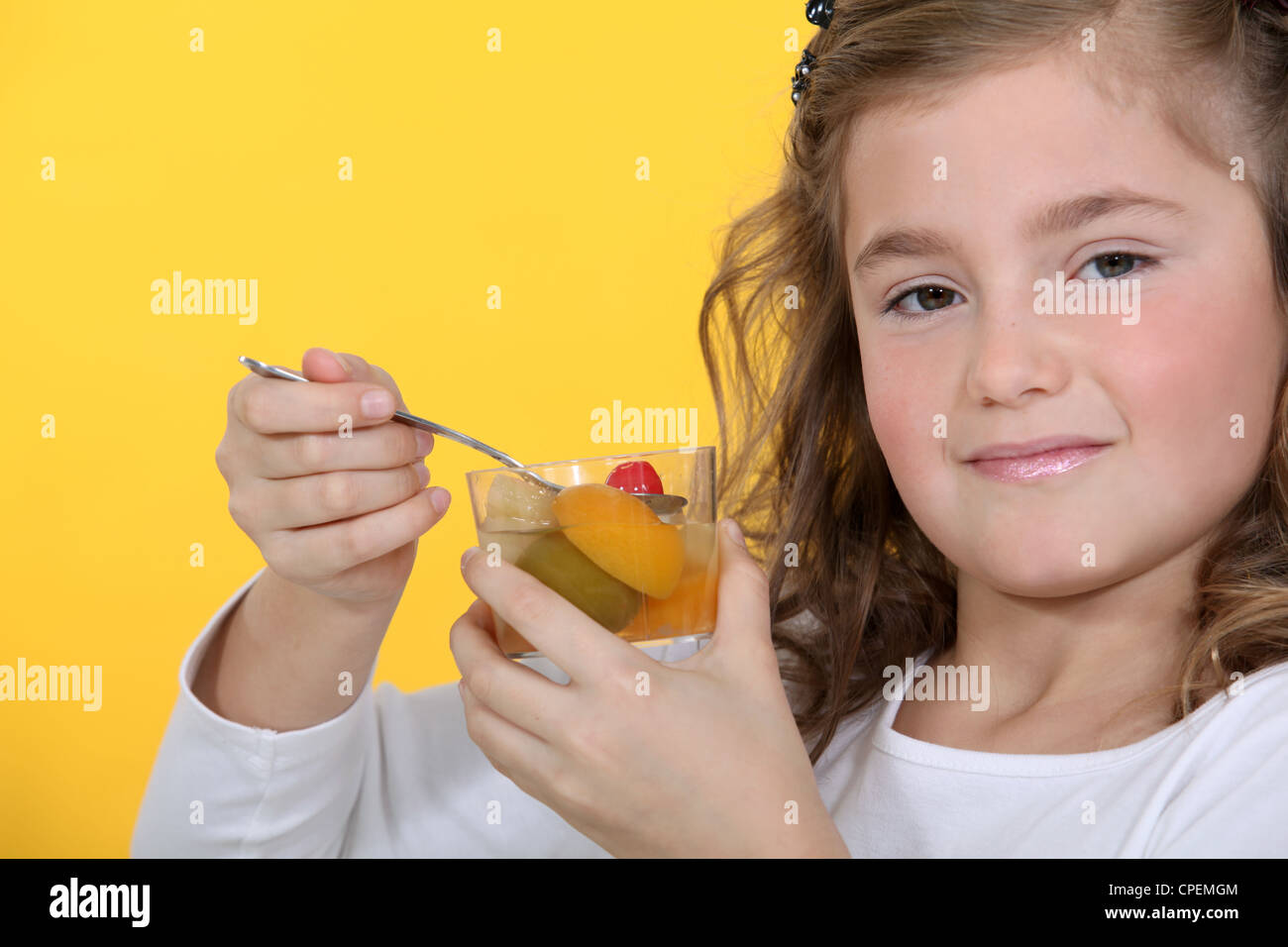 Little girl eating fruit cocktail Stock Photo