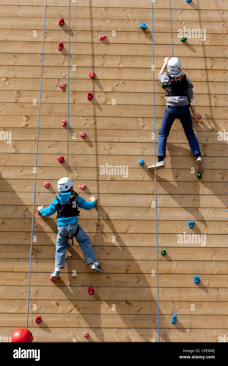 Two young boys climbing up a climbing wall outside at an outdoor pursuit center Stock Photo