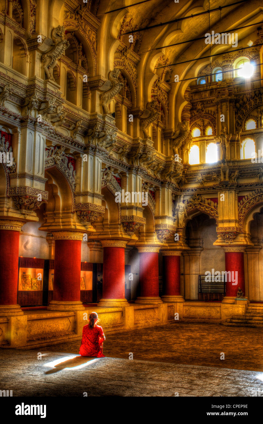 A woman in Indian dress sitting in a sunbeam in the Thirumalai Palace at Madurai, South India Stock Photo