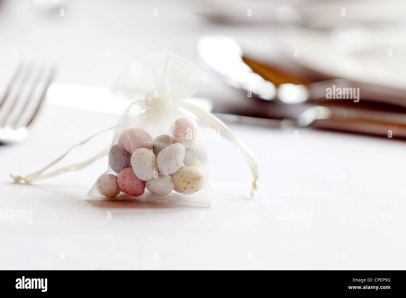 A small muslin bag of sugared almonds as a table decoration on a wedding table Stock Photo