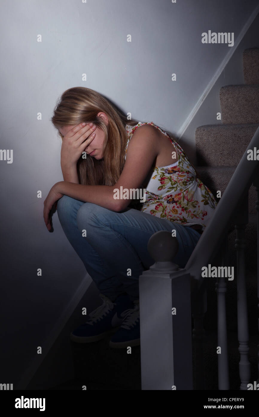 Young girl sitting on dark stairs back view Stock Photo