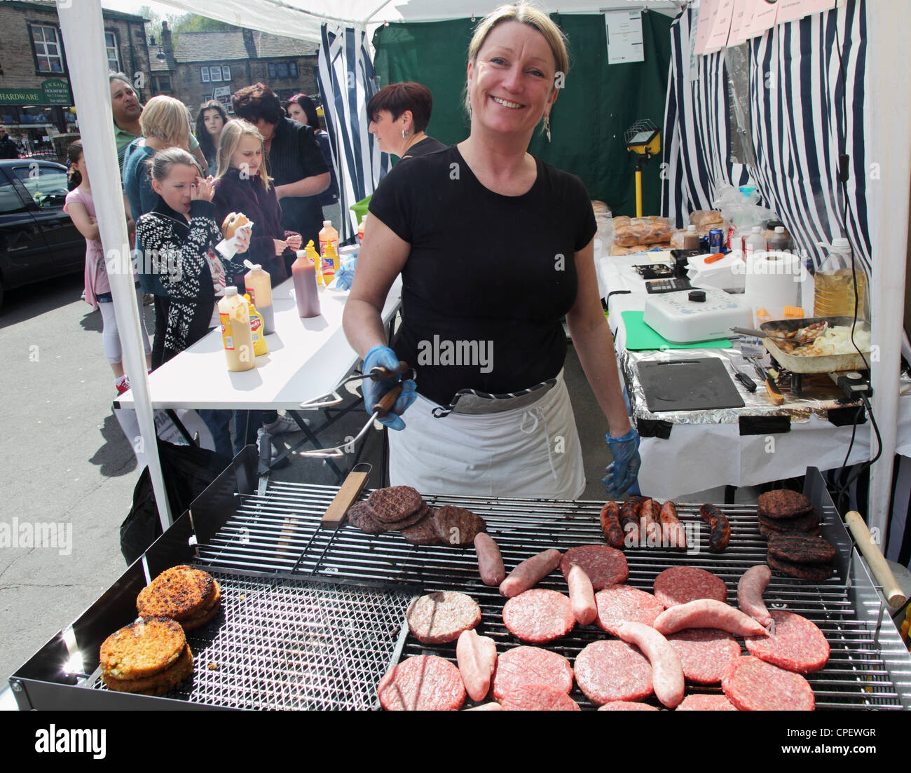 Smiling woman cooking and selling burgers and sausages at Holmfirth Festival of Folk 2012 Stock Photo