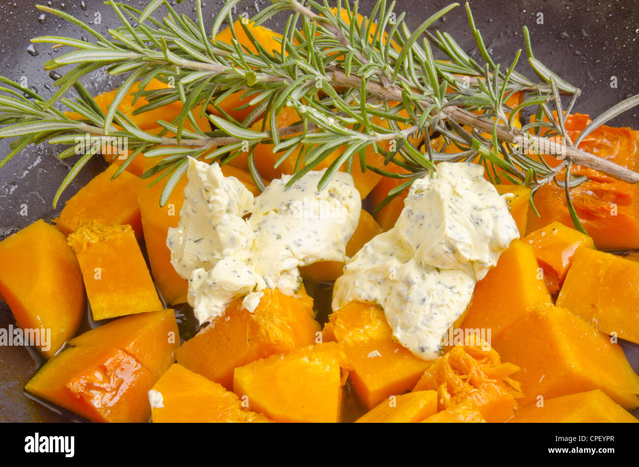 butternut pumpkin in a pan with herb butter and rosemary Stock Photo