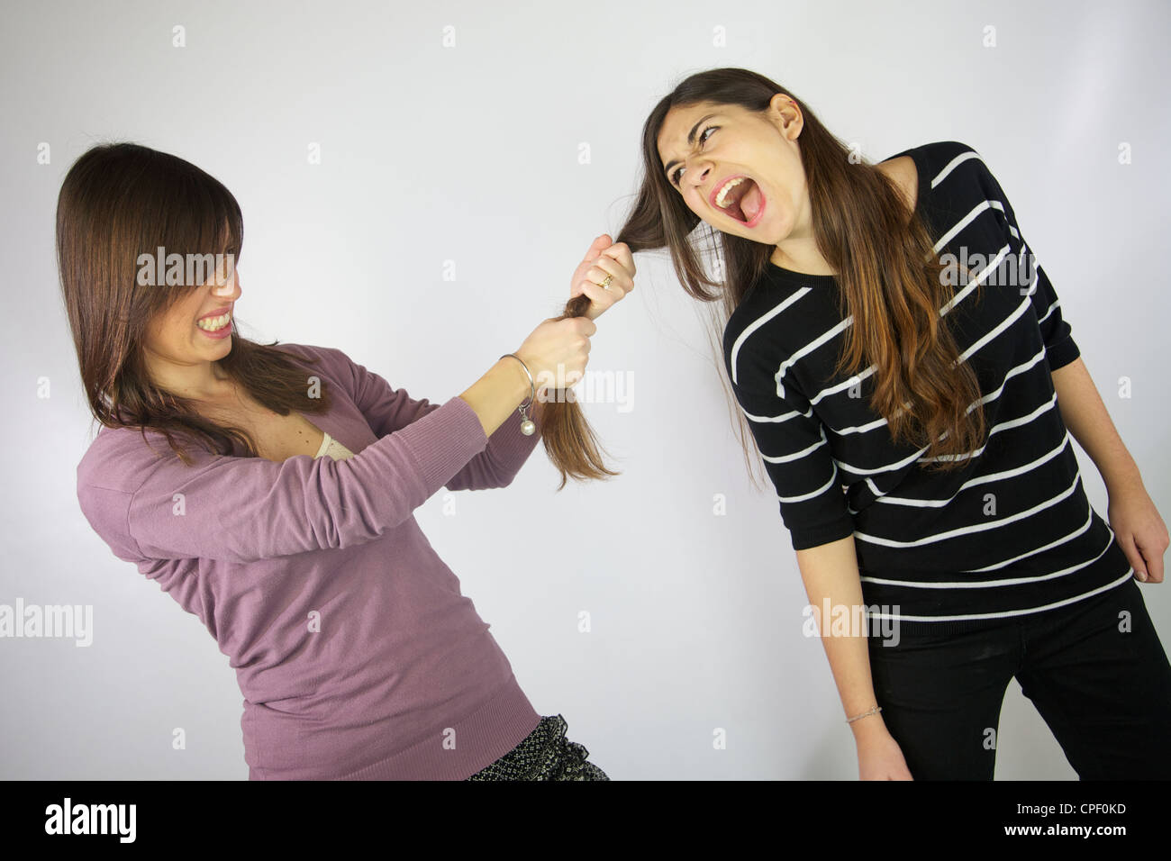 Girl pulling hard the hair to another girl that shouts Stock Photo - Alamy
