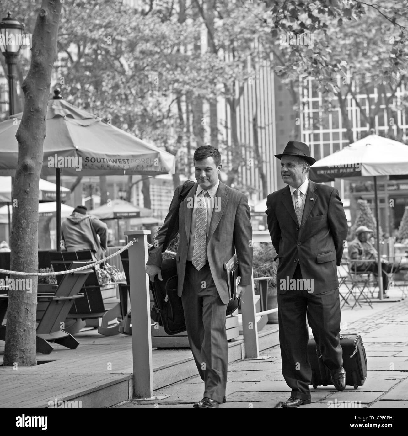 2 businessmen chat while walking through Bryant Park in New York City. Stock Photo