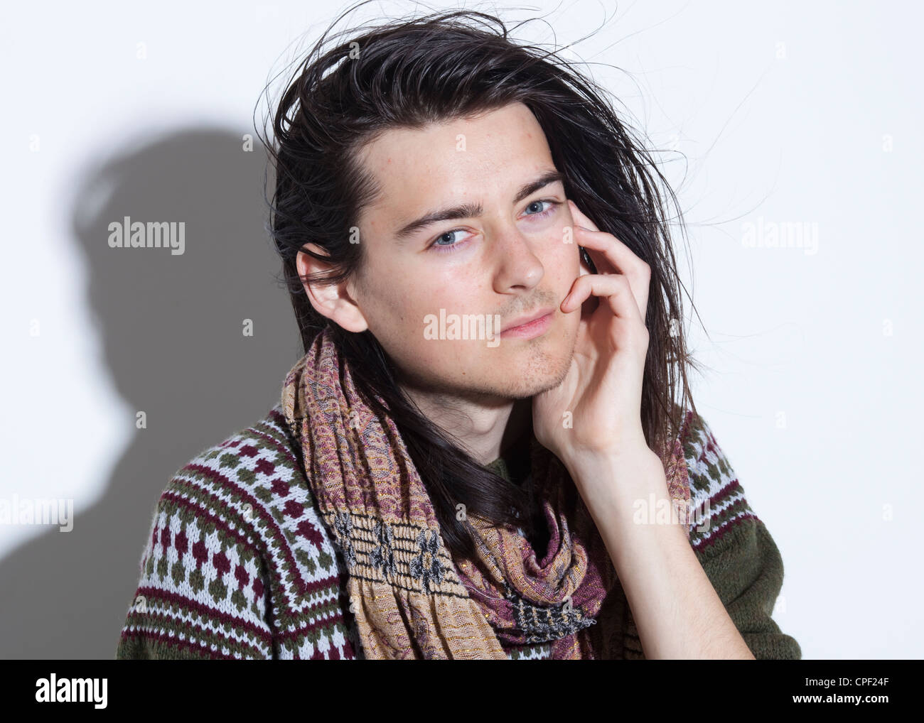 Half Length Colour Studio Portrait Of Male With Long Hair Wearing A Knitted Jumper And Scarf Left Hand Raised To Side Of Face Stock Photo Alamy