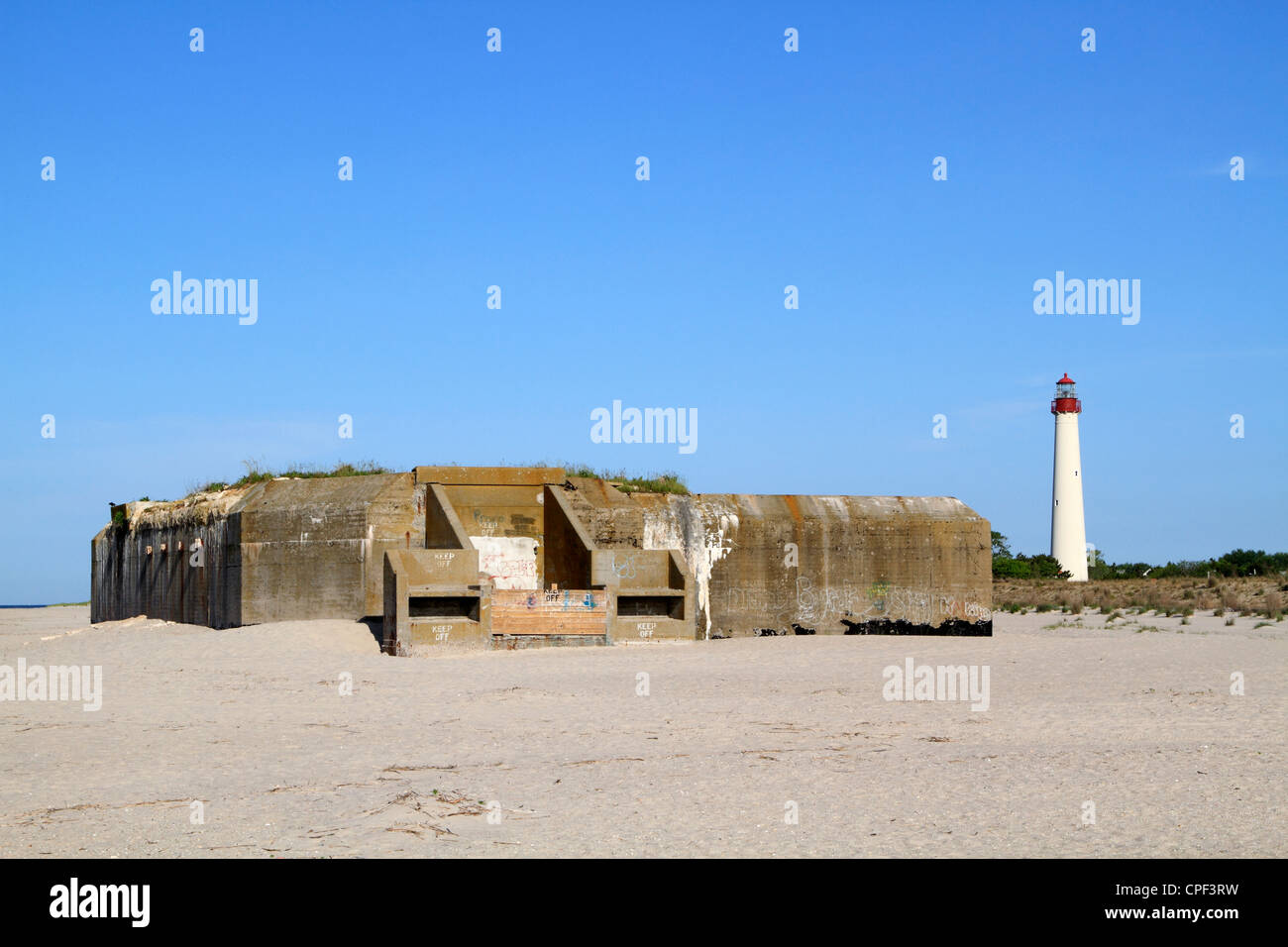 World War II artillery bunker on the beach in Cape May, New Jersey, USA. The Cape May Lighthouse can be seen to the right. Stock Photo