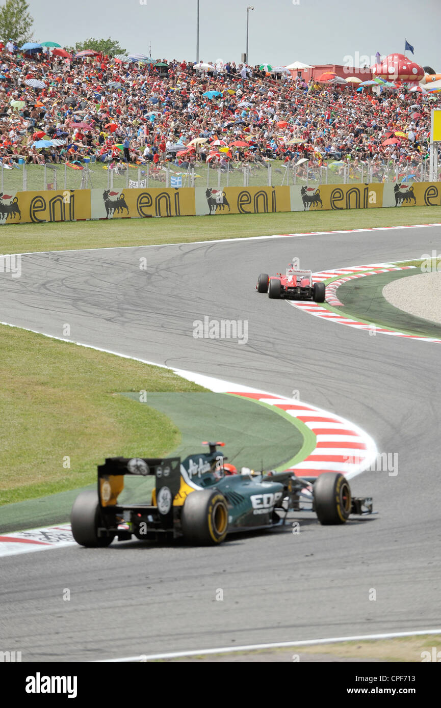 two race cars pass through curve in front of grandstand filled with ...