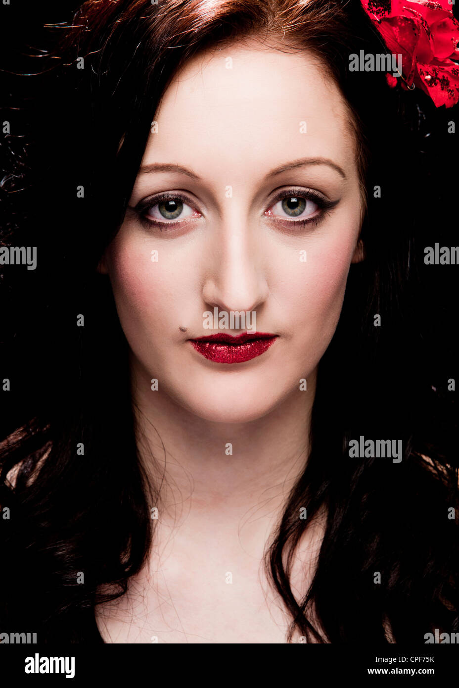 Head shot colour studio portrait of female model wearing a black dress and red lipstick looking directly into the camera Stock Photo