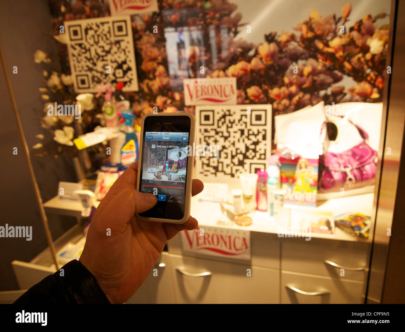 Shopping new style, man scanning qr-code with smartphone of product in shop window, to buy the product and have it shipped home. Stock Photo