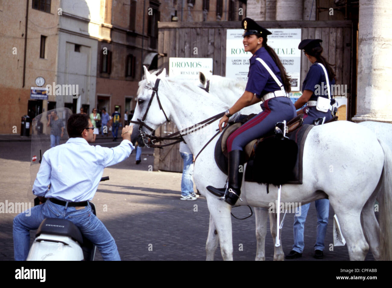 Policewomen on horseback speaking with a man Stock Photo