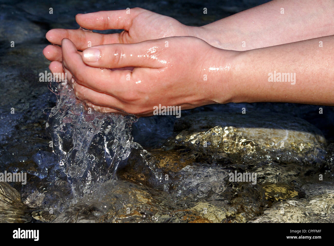 hands of a young woman refreshing in the fresh and pure water of a mountain stream Stock Photo