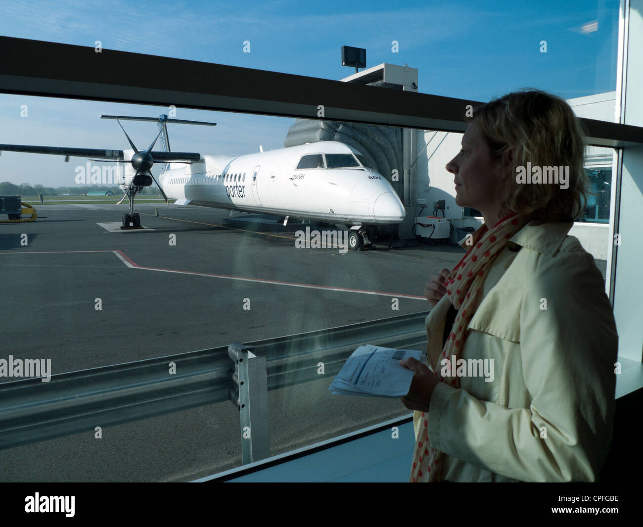 Female businesswoman looking out window as she prepares to board Porter airline plane from Billy Bishop Airport in Toronto Island Canada  KATHY DEWITT Stock Photo
