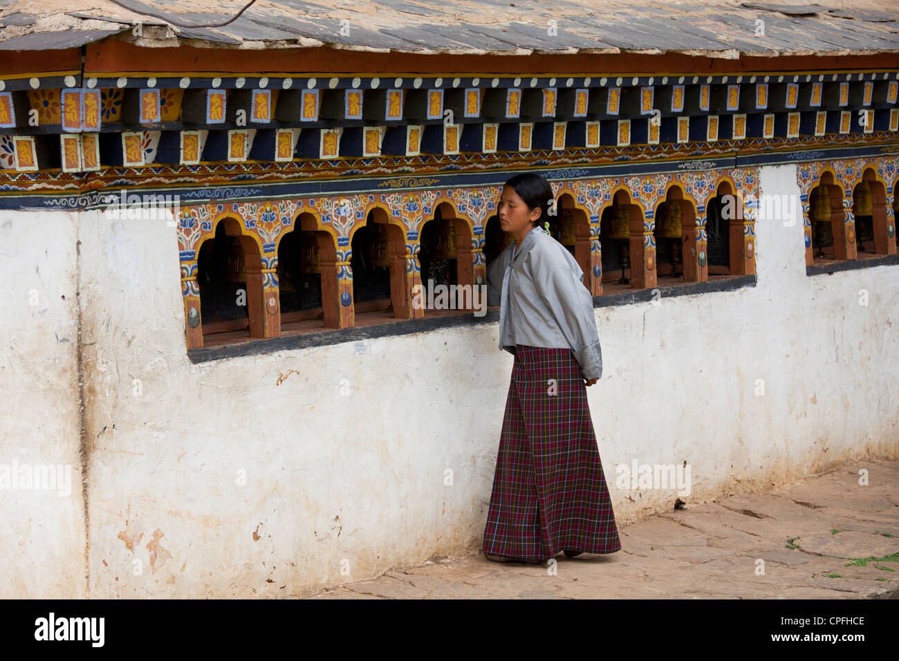 Young girl spinning prayer wheels at Chimi Lhakhang. Lobesa valley, Bhutan. Stock Photo