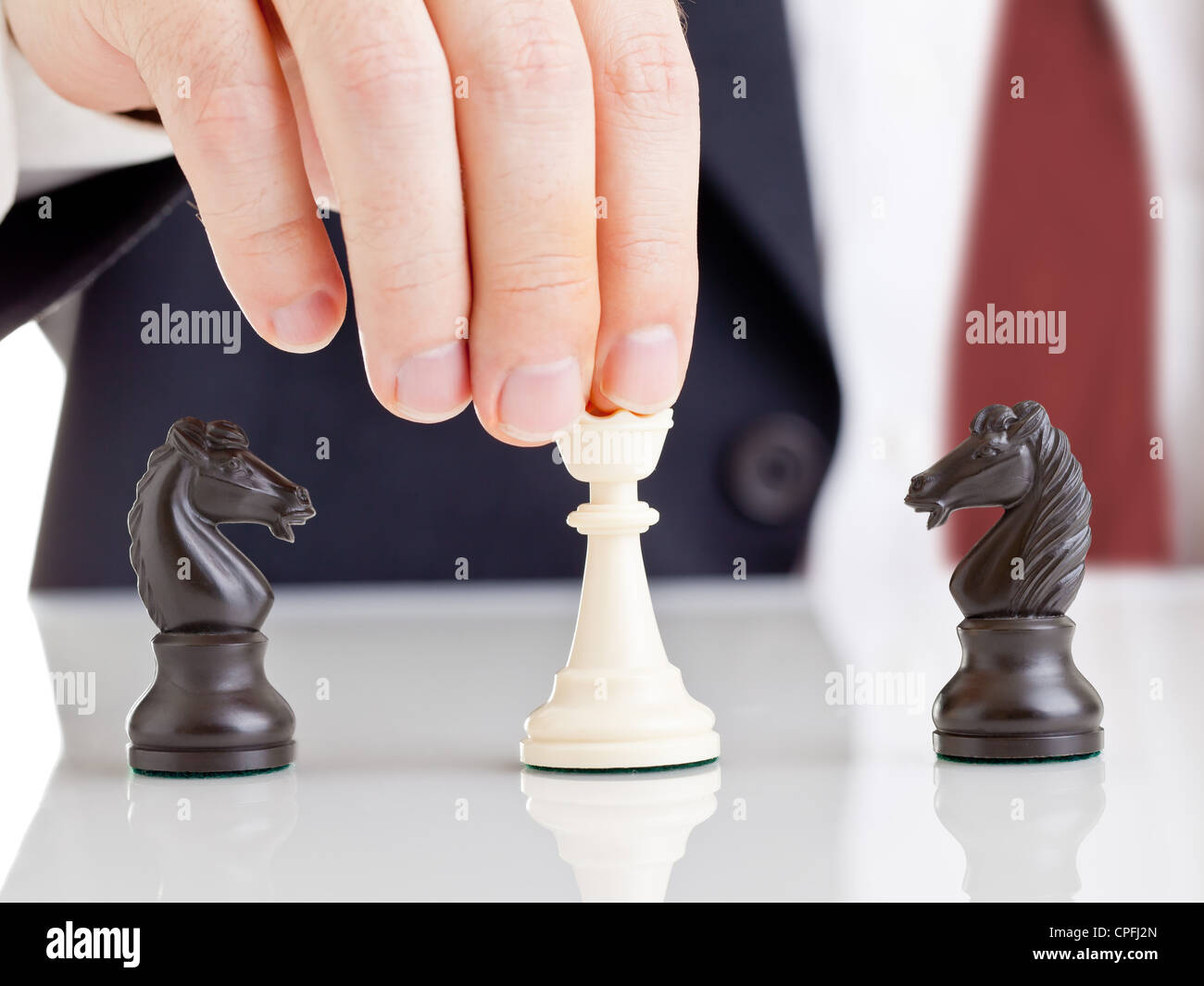 Business man holding chess queen figure between two arguing knight figures - conflict management concept Stock Photo