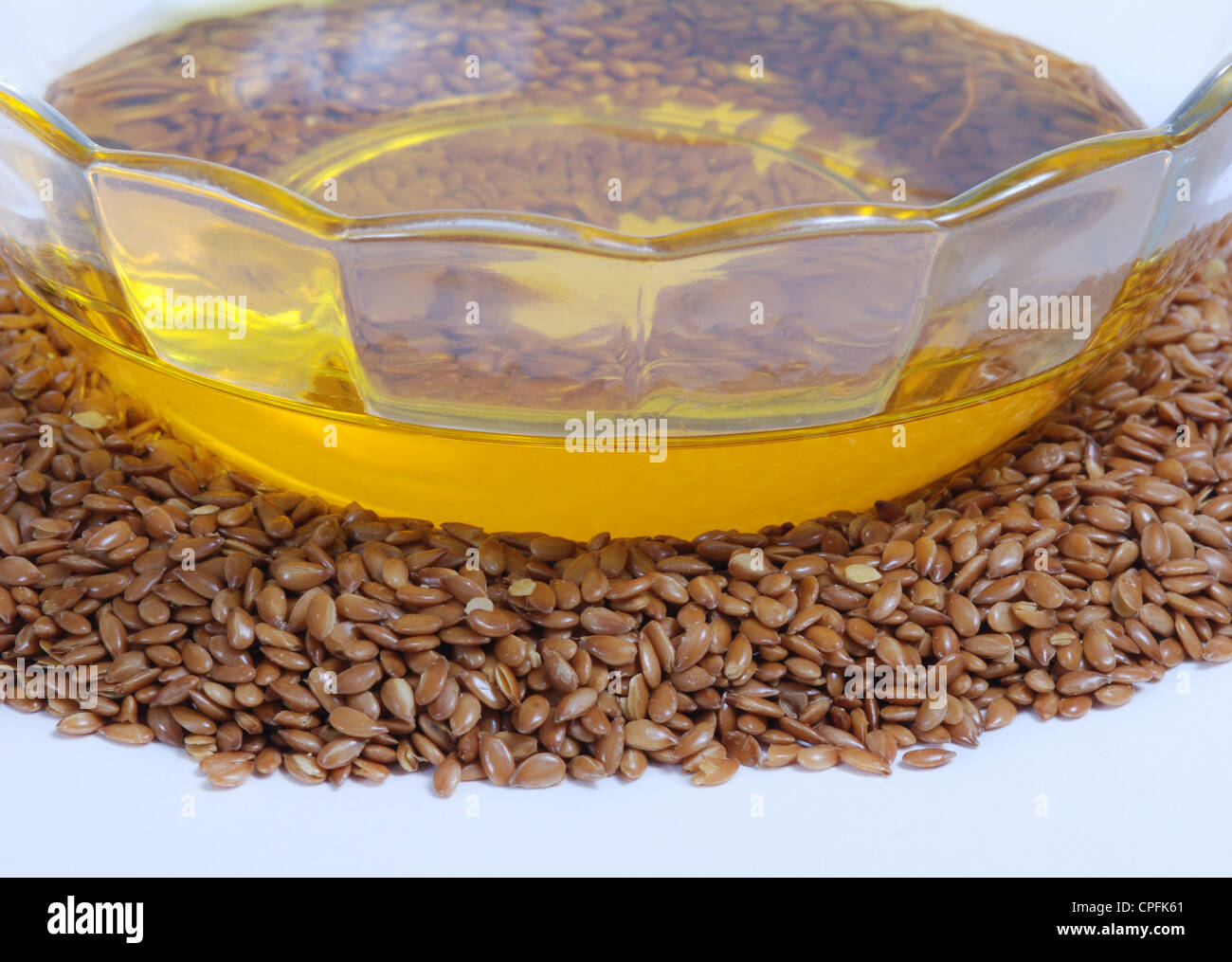 Flaxseed oil in bowl and whole flax seeds. Isolated on white Stock