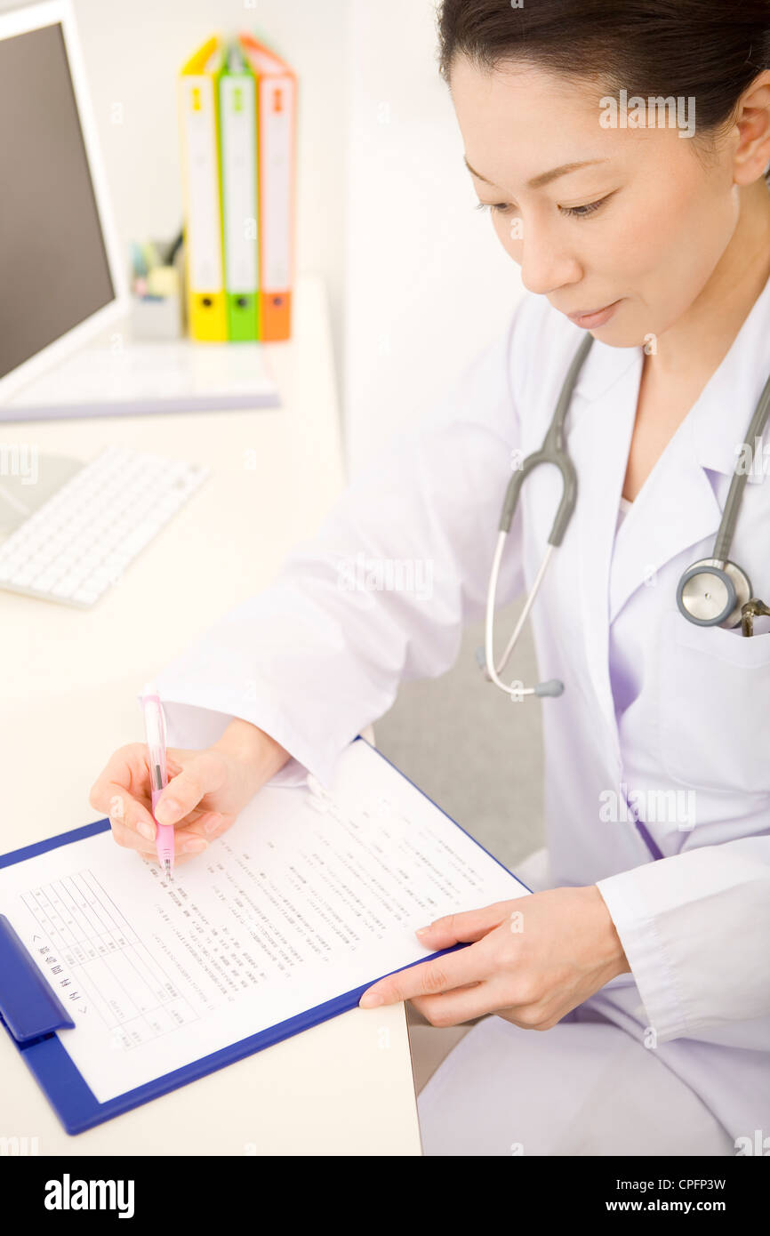 Female doctor writing in chart Stock Photo - Alamy
