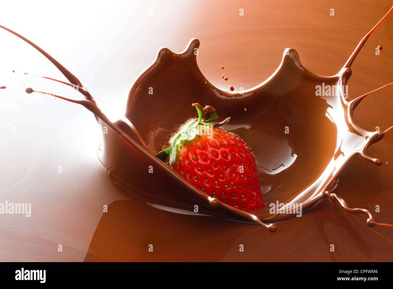 Strawberry Creating Splashing Crown In Chocolate Stock Photo