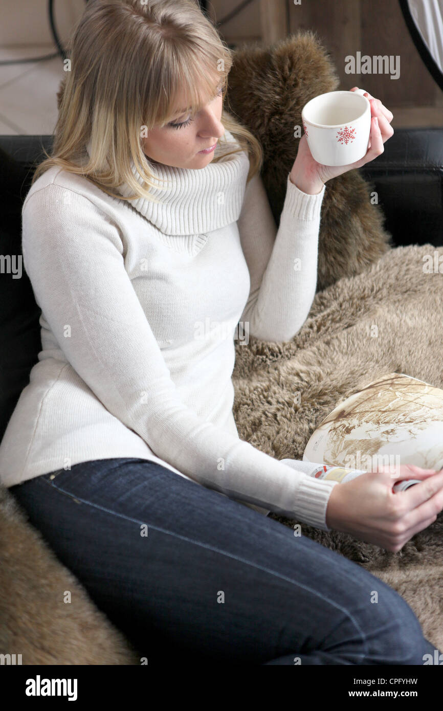 Woman relaxing on sofa with mug of coffee Stock Photo - Alamy