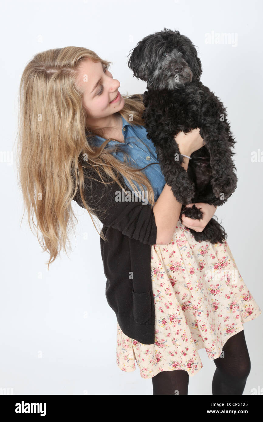 Young teenage girl standing holding a cute black dog. Stock Photo