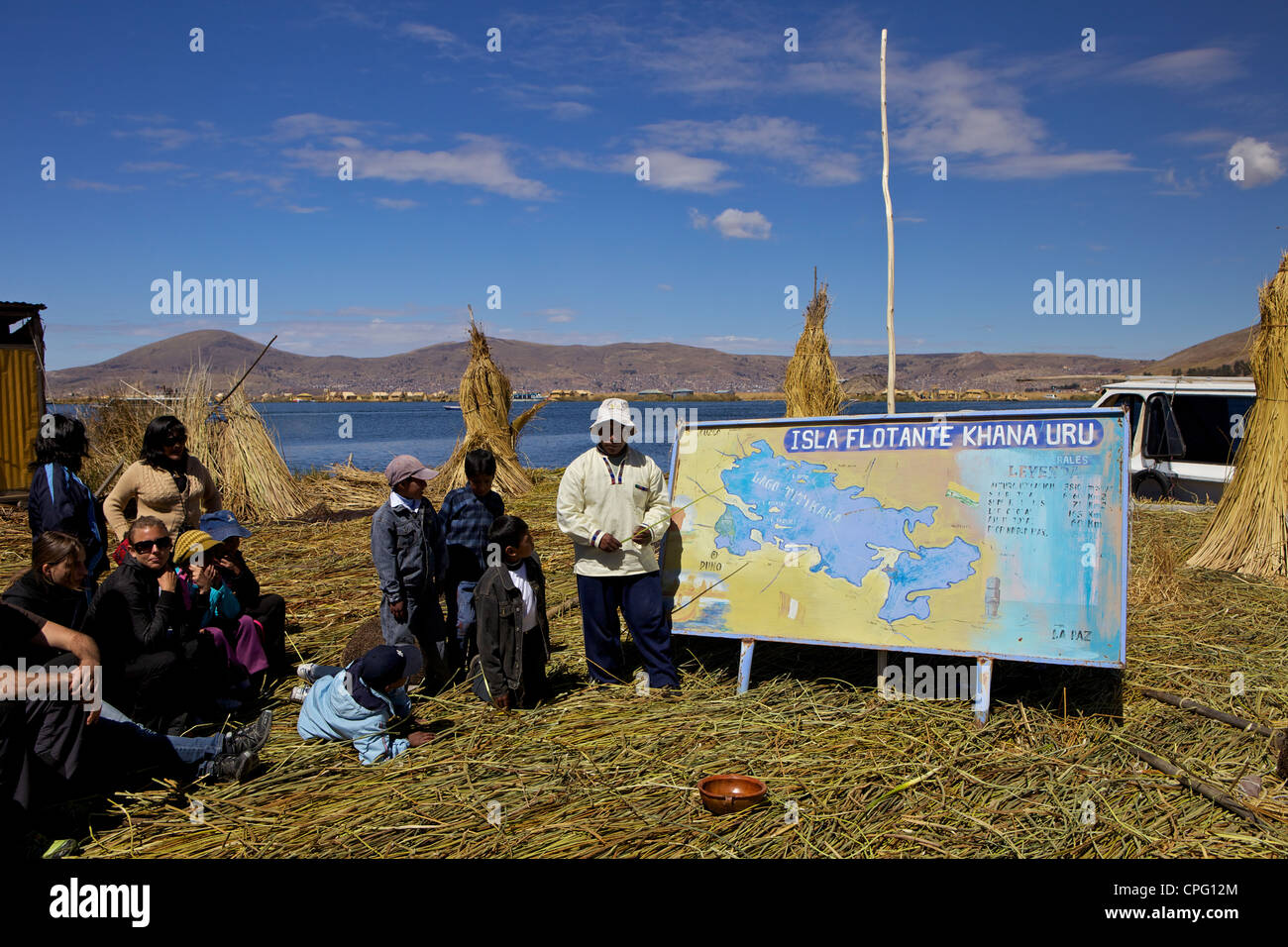 Indigenous man showing tourists map of Isla Flotante (floating islands) Lake Titicaca. South America Stock Photo