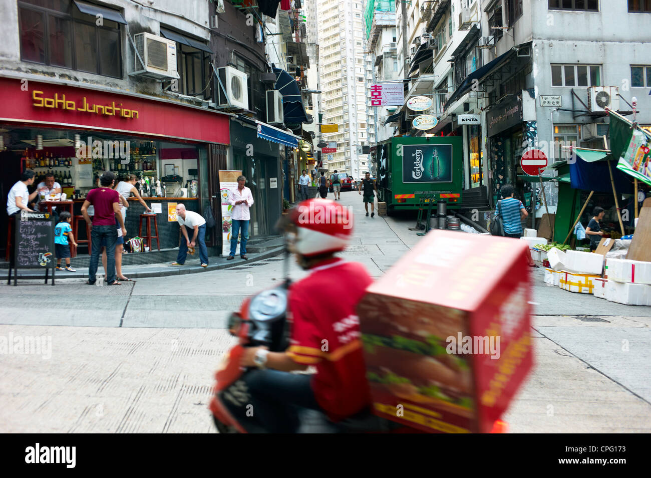 A delivery person races by a busy intersection in Soho, Central Hong Kong. Stock Photo