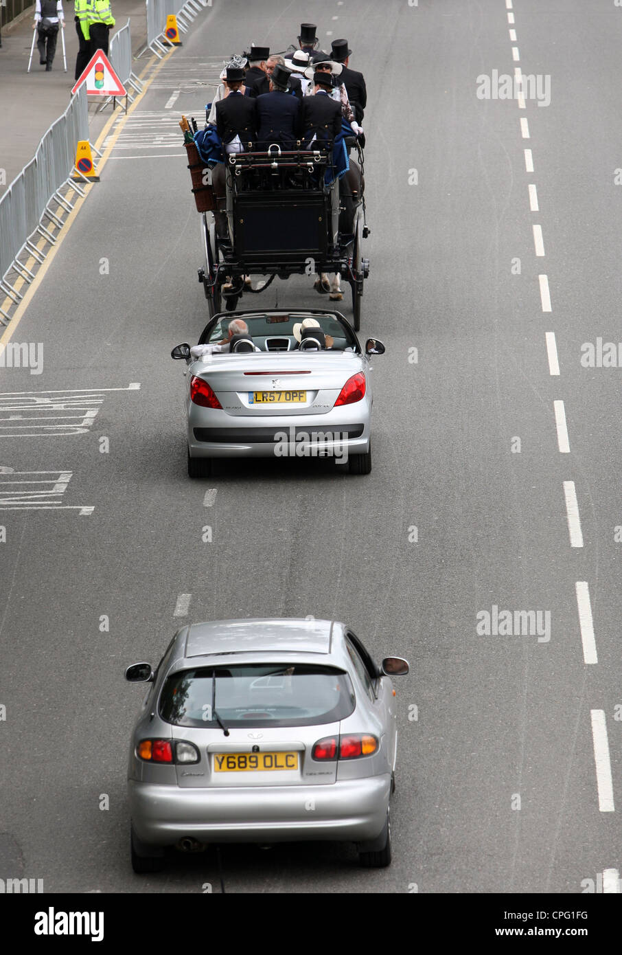 Cars driving slowly behind a horse-drawn carriage, Ascot, UK Stock Photo