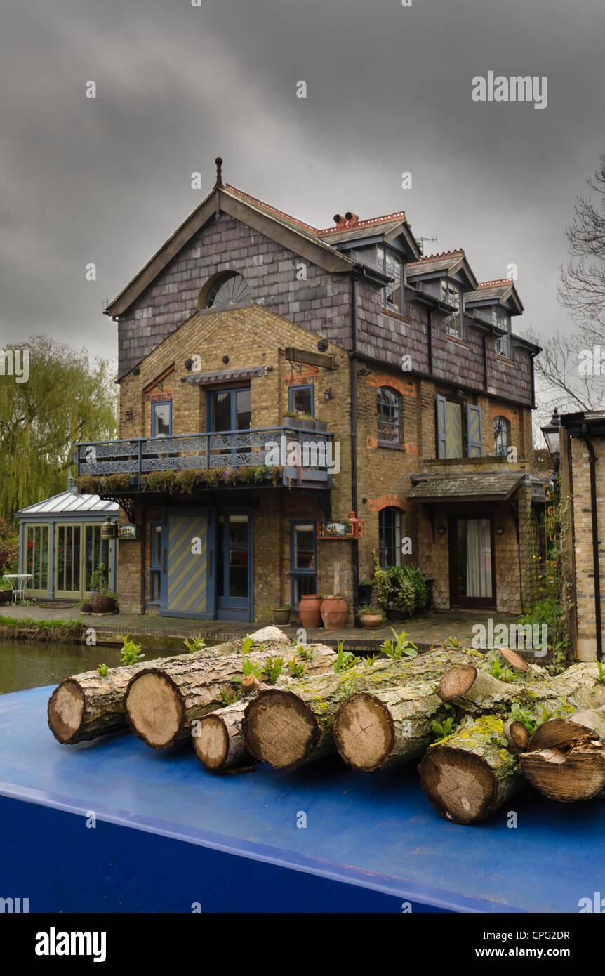 sawn logs on a narrow boat opposite the 'Warehouse' now a private home on the Grand Union Canal Berkhamsted UK Stock Photo