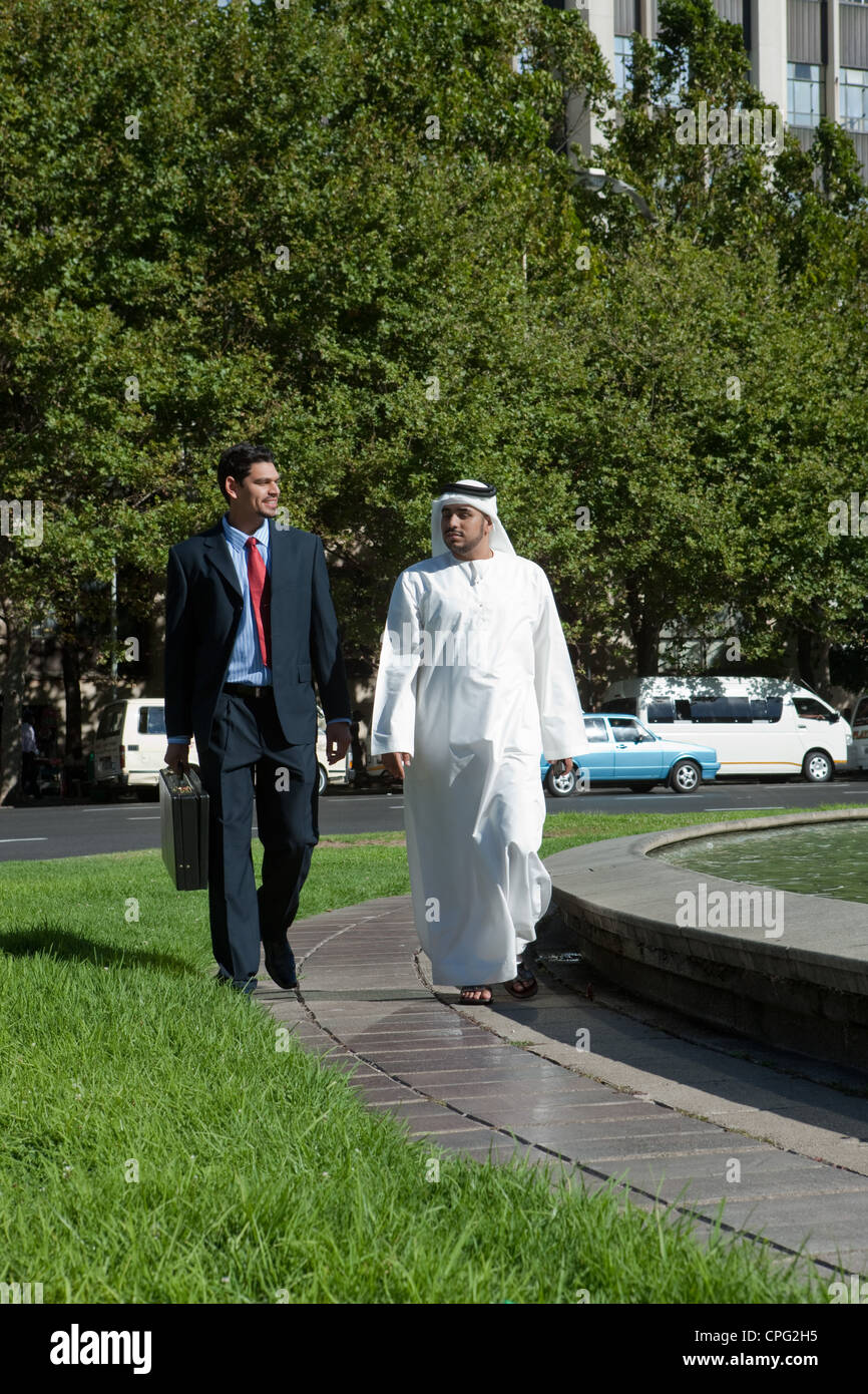 Two businessmen talking while walking at the street Stock Photo - Alamy
