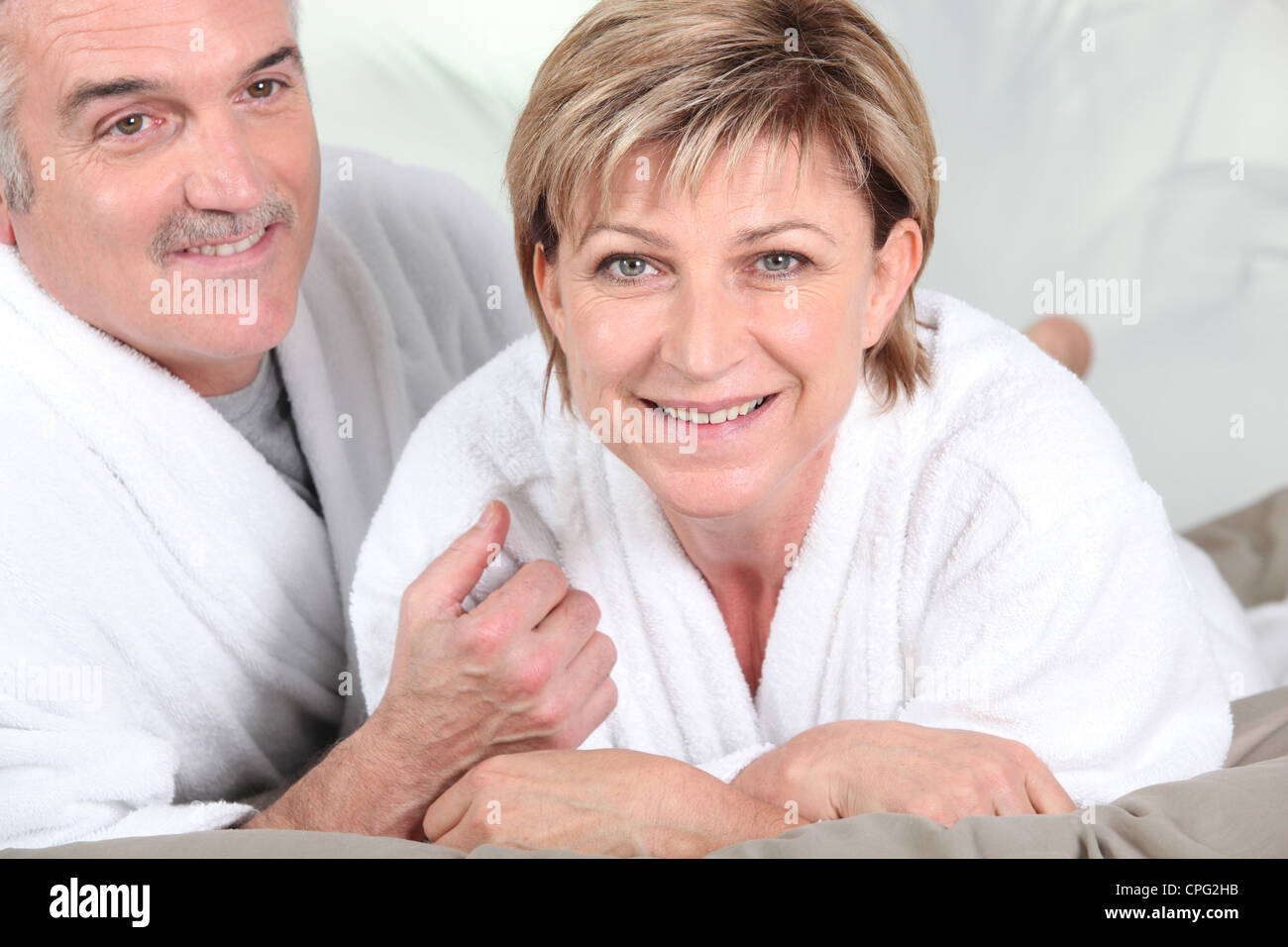 Mature couple in bed with bathrobe Stock Photo