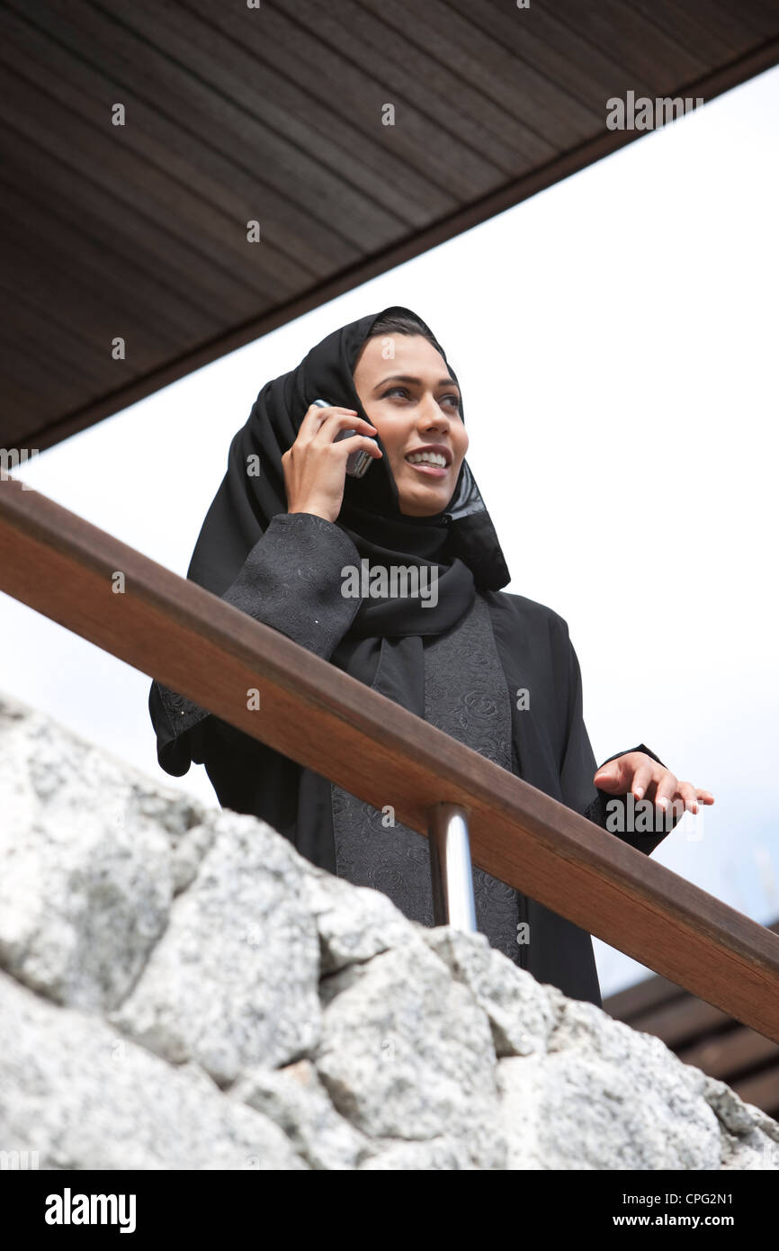 Arab woman using mobile phone in the balcony, smiling Stock Photo - Alamy