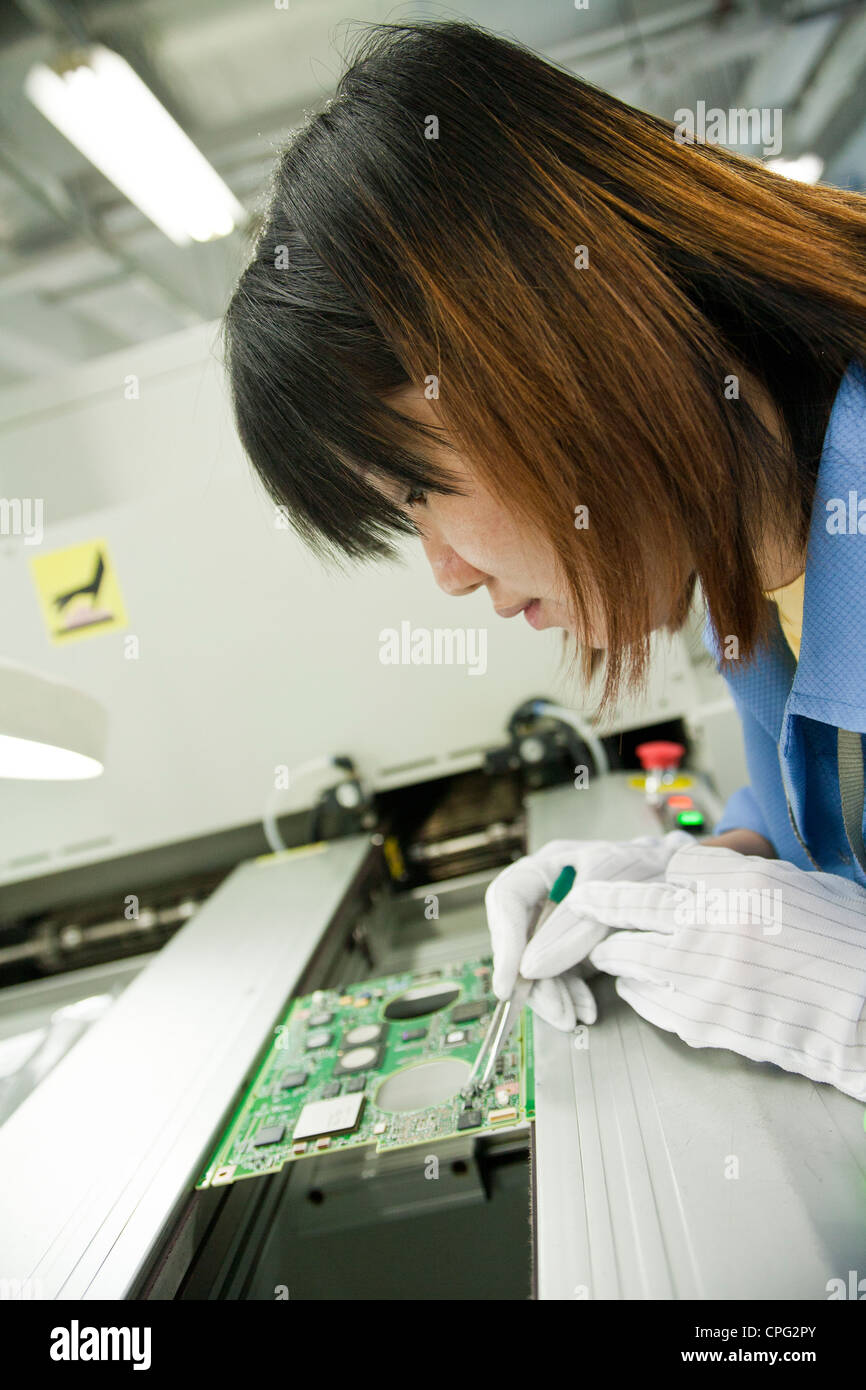 A worker inspects a printed circuit board on the assembly line at the Venture Corp. factory in Singapore Stock Photo