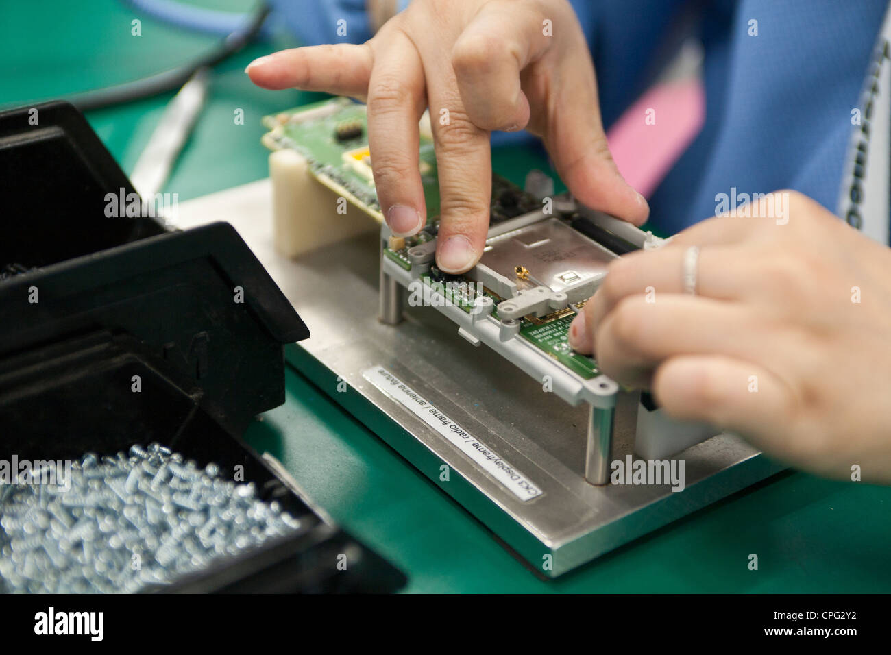 A worker assembles hand-held inventory computer devices on the assembly ...