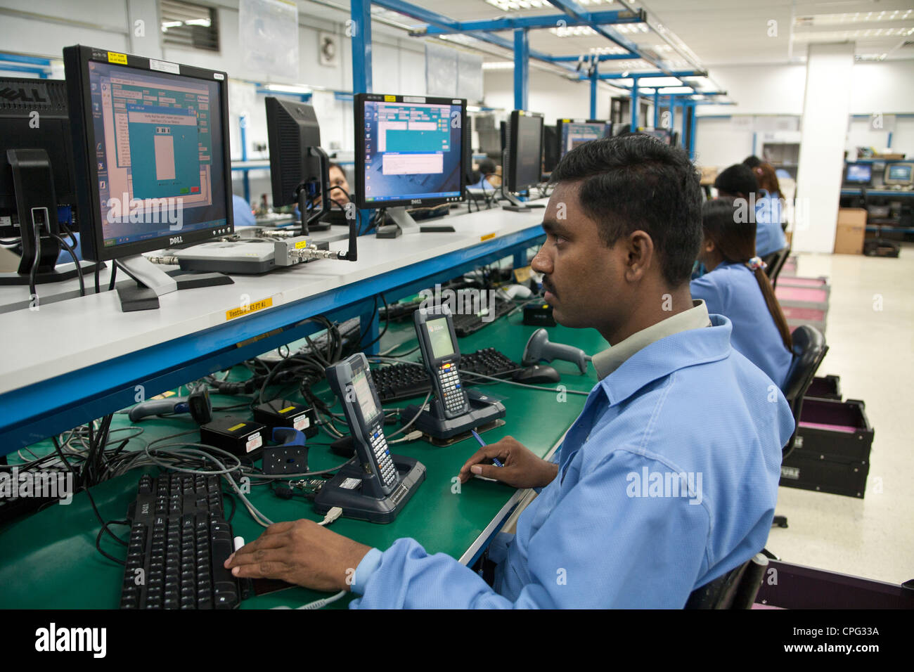 Workers test hand-held inventory computer devices on the assembly line at the Venture Corp. factory in Singapore Stock Photo