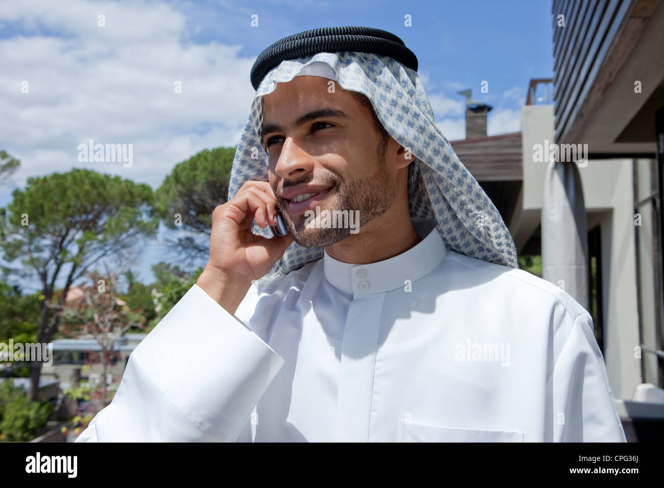 Arab man using mobile phone, standing in the balcony Stock Photo - Alamy