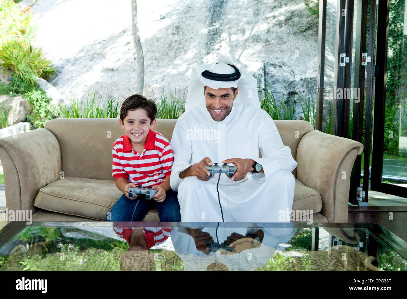 Arab father and son playing video game together. Stock Photo