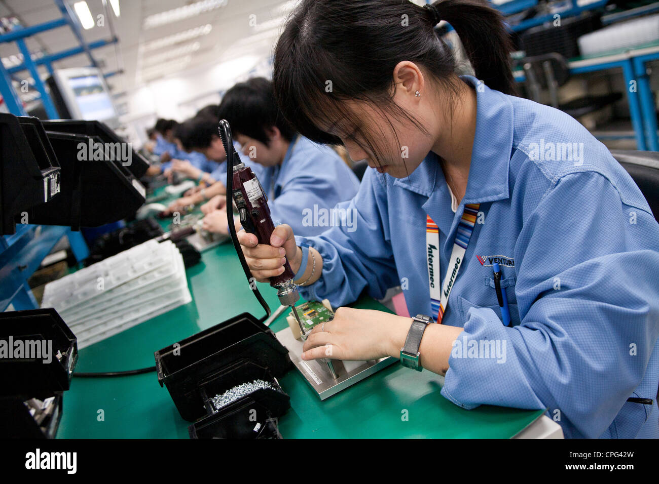 Workers assemble hand-held inventory computer devices on the assembly line at the Venture Corp. factory in Singapore Stock Photo