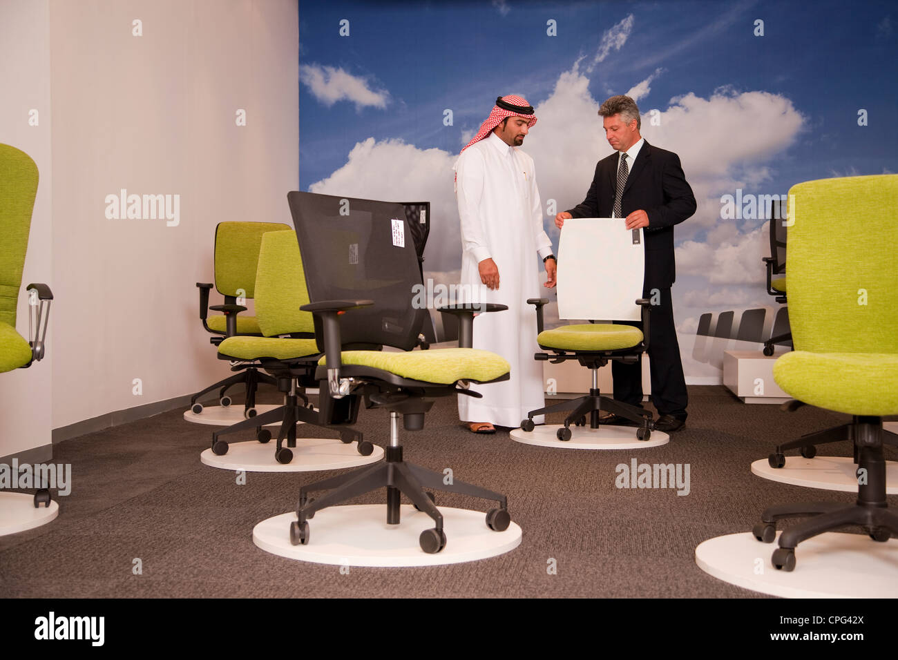 Salesman assisting arab man shopping for office chairs in furniture store. Stock Photo